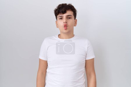 Téléchargez les photos : Jeune homme non binaire portant un t-shirt blanc décontracté faisant visage de poisson avec des lèvres, geste fou et comique. expression drôle. - en image libre de droit