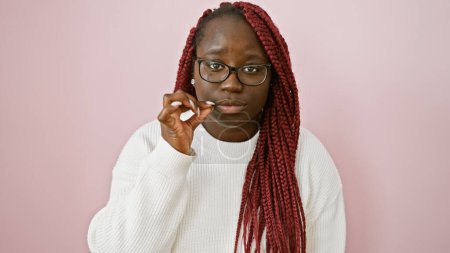 Photo for African american woman with braids gestures for silence against a pink background - Royalty Free Image