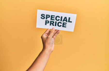 Photo for Hand of caucasian man holding paper with special price message over isolated yellow background - Royalty Free Image