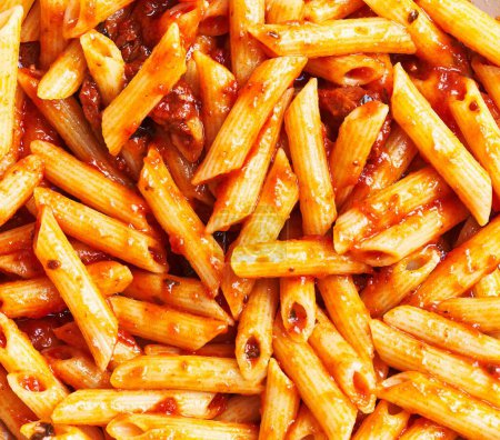Téléchargez les photos : Gros plan de délicieuses pâtes penne à la sauce tomate, parfaitement cuites pour des images sur le thème de la cuisine italienne. - en image libre de droit