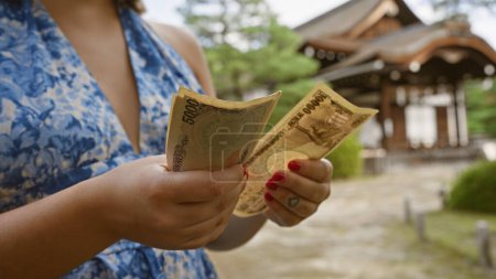 Kaukasische junge Frauenhände beim Zählen des Reichtums japanischer Yen-Banknoten an traditionellem heian jingu, kyoto, einem Symbol des asiatischen Finanzreichtums