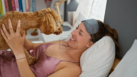 Foto de Joven mujer caucásica con perro acostado en la cama juntos jugando en el dormitorio - Imagen libre de derechos