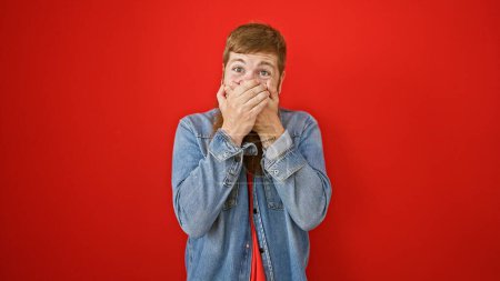 Photo for Wow! young, handsome, red-haired man standing amazed, covering face with hands over isolated red background. casually cheerful expression of surprise. quite the irish expression eh? - Royalty Free Image