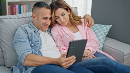 Photo for Man and woman couple using touchpad sitting on sofa at home - Royalty Free Image