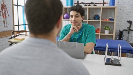 A male physiotherapist in a clinic listens attentively to a male patient during a rehabilitation session.