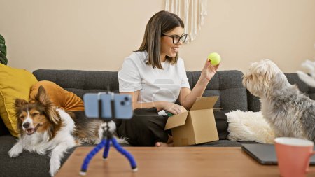 Hispanic woman unpacking box playing with dogs in living room
