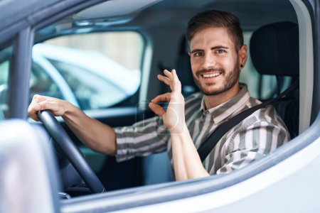 Photo for Hispanic man with beard driving car doing ok sign with fingers, smiling friendly gesturing excellent symbol - Royalty Free Image