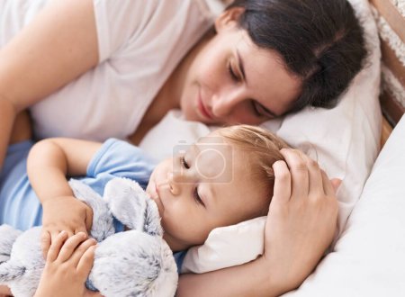 Foto de Madre e hijo durmiendo en la cama abrazando muñeca en el dormitorio - Imagen libre de derechos