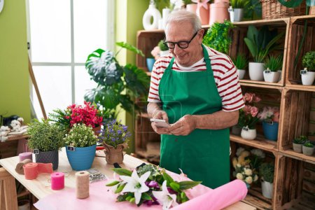 Photo for Middle age grey-haired man florist make photo to flowers by smartphone at flower shop - Royalty Free Image