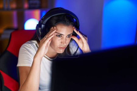 Foto de Joven hermosa mujer hispana streamer estresado usando computadora en sala de juegos - Imagen libre de derechos
