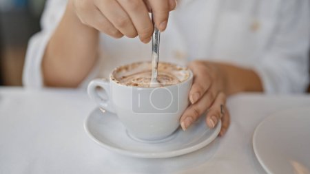 Téléchargez les photos : Jeune femme buvant du café assis sur la table au restaurant - en image libre de droit