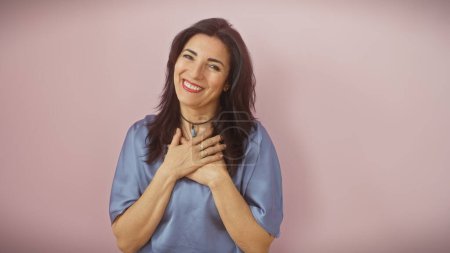 Foto de Mujer hispana madura feliz con ropa azul aislada sobre un fondo rosa expresando alegría y positividad. - Imagen libre de derechos