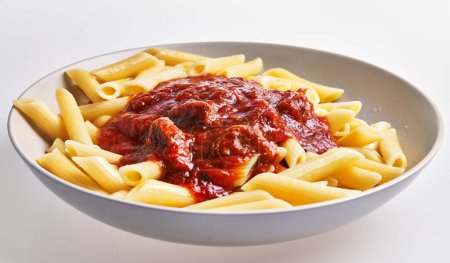 Foto de Un plato de pasta de penne rematado con rica salsa de tomate sirve como una apetitosa cocina italiana representativa. - Imagen libre de derechos