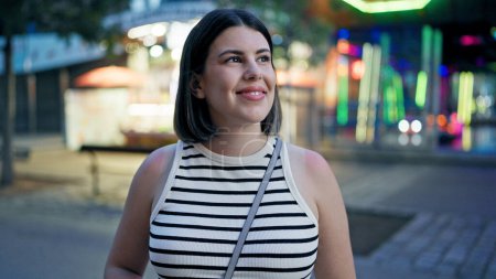 Junge schöne hispanische Frau lächelt sich im Wiener Prater um