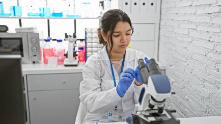 Foto de Científica hispana trabajando con un microscopio en un moderno entorno de laboratorio. - Imagen libre de derechos