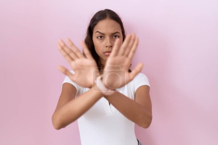 Téléchargez les photos : Jeune femme hispanique portant casual blanc t-shirt rejet expression croisant les bras et les paumes faisant signe négatif, visage en colère - en image libre de droit