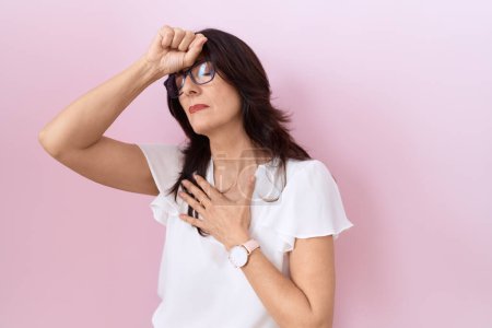 Photo for Middle age hispanic woman wearing casual white t shirt and glasses touching forehead for illness and fever, flu and cold, virus sick - Royalty Free Image