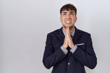 Téléchargez les photos : Jeune homme d'affaires hispanique portant costume et cravate mendier et prier avec les mains ainsi que l'expression de l'espoir sur le visage très émotionnel et inquiet. mendier. - en image libre de droit