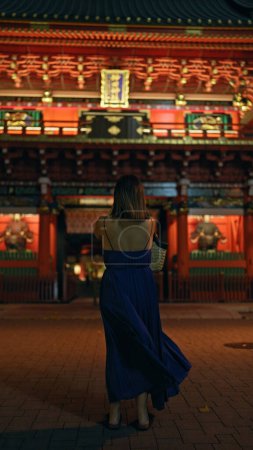 Téléchargez les photos : Belle femme hispanique plonge dans la spiritualité, priant sous le ciel clair de lune au temple japonais traditionnel dans la nuit mystérieuse de tokyo - en image libre de droit