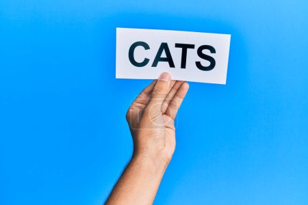 Hand of caucasian man holding paper with cats word over isolated blue background