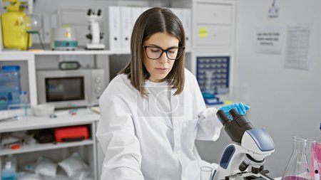 Hispanische Wissenschaftlerin analysiert Proben unter dem Mikroskop im Labor
