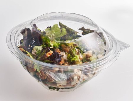 Una ensalada fresca lista para comer en un recipiente de plástico sellado que muestra una alimentación saludable.