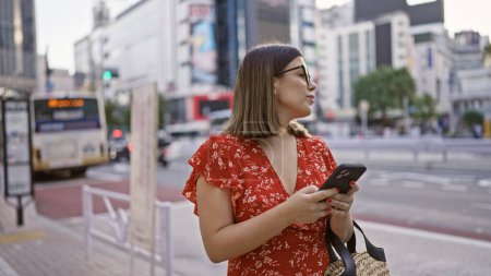 Téléchargez les photos : Belle femme hispanique avec des lunettes à Tokyo, connexion numérique via smartphone dans les rues de la ville - en image libre de droit
