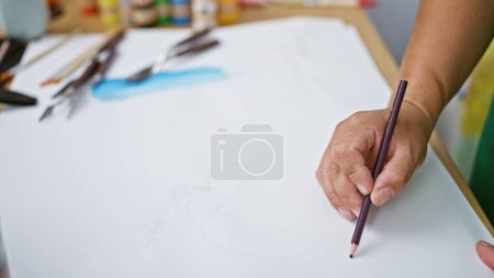 Photo for Passionate young latin artist immersed in drawing on his notebook, stationed at the heart of a vibrant art studio - Royalty Free Image
