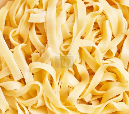 Foto de Vista de cerca de la pasta italiana sin cocer tagliatelle con un aspecto texturizado y amarillo. - Imagen libre de derechos