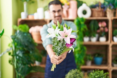 Photo for Young hispanic man florist holding bouquet of flowers at flower shop - Royalty Free Image