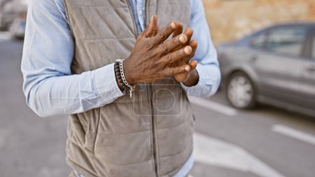 Close-up of a stylish black man's hands with bracelet in a city street setting