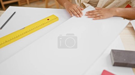 Téléchargez les photos : Artisanat au travail, les mains de la jeune femme hispanique mesurant habilement la planche de bois dans son atelier de menuiserie, marquant le futur chef-d'œuvre du meuble - en image libre de droit