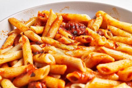 Téléchargez les photos : Vue rapprochée de délicieuses pâtes penne en sauce tomate sur une assiette en céramique, cuisine italienne. - en image libre de droit