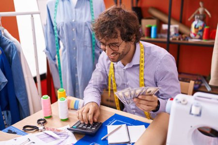 Téléchargez les photos : Young hispanic man tailor counting dollars at atelier - en image libre de droit