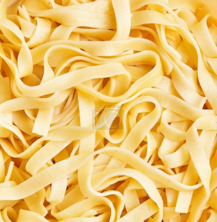 Close-up of uncooked tagliatelle noodles showcasing their texture against a full-frame background.