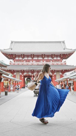 Photo for Effervescent hispanic woman dances joyfully, spinning in beautiful dress amidst senso-ji temple's splendid architecture in tokyo. touring japan, she exudes happiness in urban vacation adventure. - Royalty Free Image
