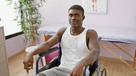 Schöner erwachsener schwarzer Mann im Rollstuhl posiert drinnen in einer Reha-Klinik