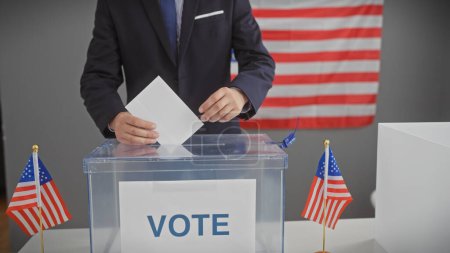 Téléchargez les photos : Un homme hispanique votant dans un centre électoral américain, avec des drapeaux américains soulignant le cadre démocratique. - en image libre de droit