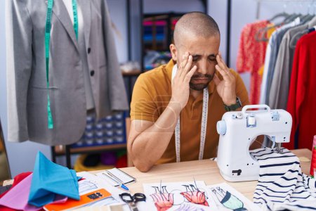 Téléchargez les photos : Jeune tailleur latino-américain stressé en utilisant une machine à coudre à l'atelier - en image libre de droit