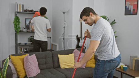 Two men cleaning and organizing a modern living room in a shared apartment, showcasing teamwork and household chores.