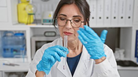 Photo for Concentrated mature woman scientist examining a test tube in a modern laboratory setting. - Royalty Free Image