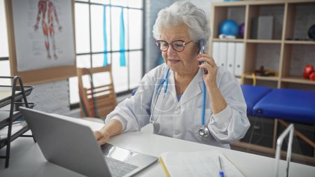 Eine medizinische Fachangestellte berät eine Patientin am Telefon, während sie an einem Laptop in einer Arztpraxis arbeitet.