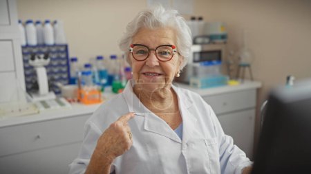 Científica senior de confianza con el pelo gris apuntándose a sí misma en un entorno de laboratorio
