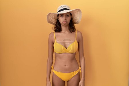 Photo for Young hispanic woman wearing bikini and summer hat depressed and worry for distress, crying angry and afraid. sad expression. - Royalty Free Image