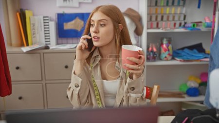 A young redhead woman multitasks with a phone and coffee in a bustling tailor shop.