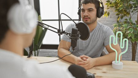 Téléchargez les photos : Deux hommes en conversation dans un studio de podcast avec microphones et écouteurs. - en image libre de droit