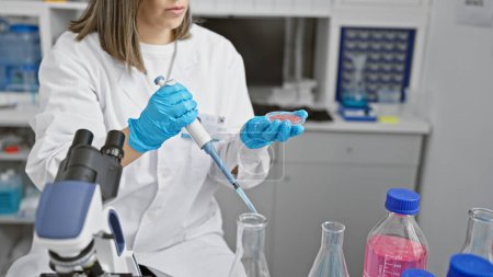 Photo for Focused woman in lab conducts experiment with pipette and test tube, in an indoor laboratory setting. - Royalty Free Image