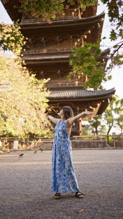 Téléchargez les photos : Femme hispanique brune joyeuse accueillant la joie à bras ouverts, regardant autour du beau temple to-ji, se délectant de la beauté de la tour de kyoto - en image libre de droit
