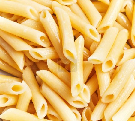 Close-up of uncooked penne pasta arranged randomly, portraying italian cuisine essentials.