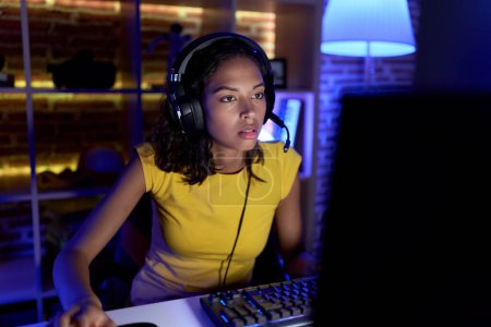 Téléchargez les photos : Young african american woman streamer playing video game using computer at gaming room - en image libre de droit